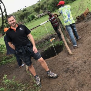Bedrock Realty owner John Savard is pictured in front of a well being built in Uganda, with community workers behind him